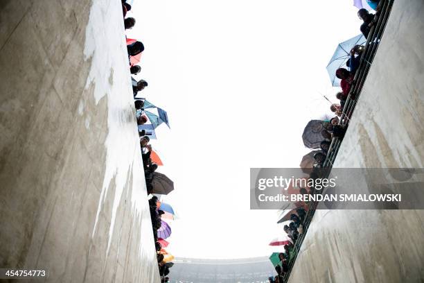 People wait for the arrival of US President Barack Obama during the memorial service for late South African President Nelson Mandela at Soccer City...