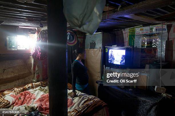 Woman watches the official memorial service for Nelson Mandela on a television inside her makeshift home in Alexandra Township on December 10, 2013...