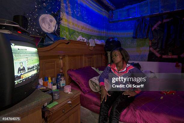 Janet Loluchiano watches the official memorial service for Nelson Mandela on a television inside her home in Alexandra Township on December 10, 2013...