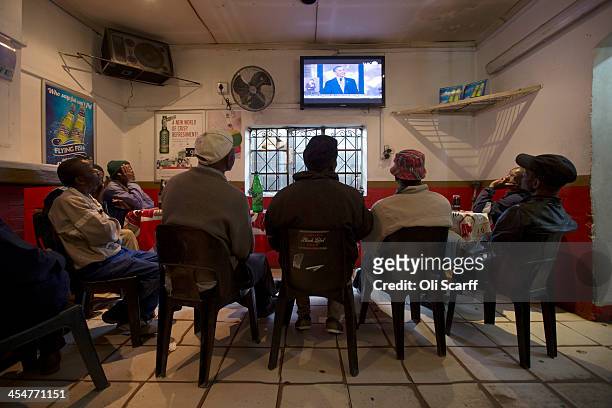 Group of men watch US President Barack Obama address the official memorial service for Nelson Mandela on a television inside the Carpet House bar in...