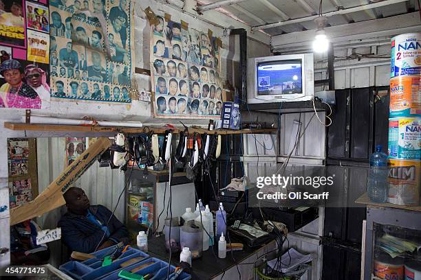 Man watches the official memorial service for Nelson Mandela on a television inside a barbers shop in Alexandra Township on December 10, 2013 in...