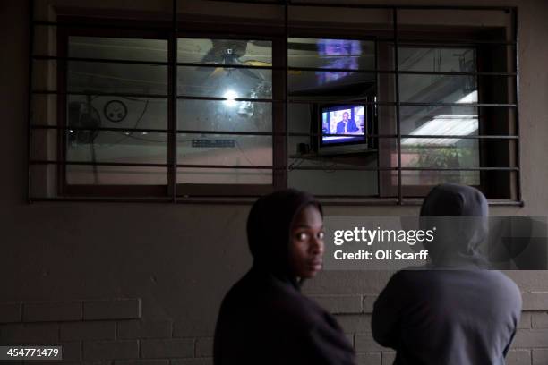 Men watch the official memorial service for Nelson Mandela on a television inside the Carpet House bar in Alexandra Township on December 10, 2013 in...