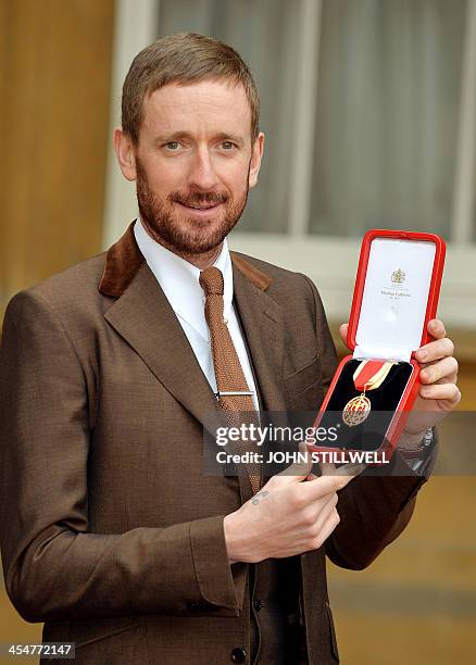 British cyclist Bradley Wiggins poses holding his medal after being appointed a Knights Bachelor by Britain's Queen Elizabeth II at an investiture...