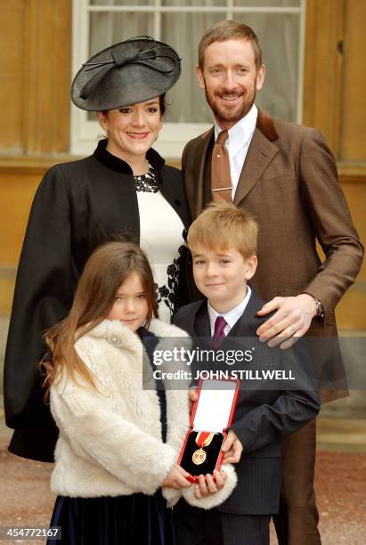 British cyclist Bradley Wiggins poses with his wife Catherine , and children Isabella and Ben holding his medal after being appointed a Knights...