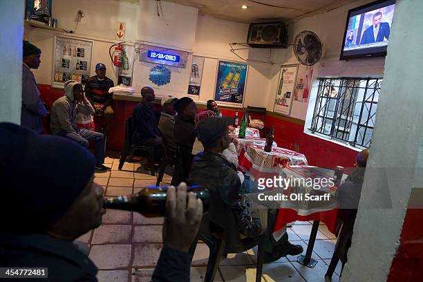 Men watch U.S President Barack Obama address the official memorial service for Nelson Mandela on a television inside the Carpet House bar in...