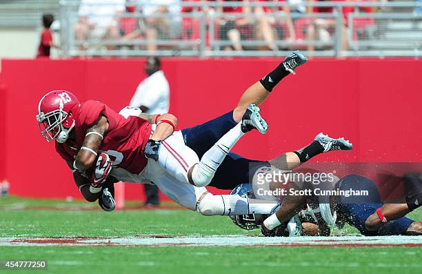 ArDarius Stewart of the Alabama Crimson Tide is tackled by Sharrod Neasman and Grant Helm of the Florida Atlantc Owls at Bryant-Denny Stadium on...