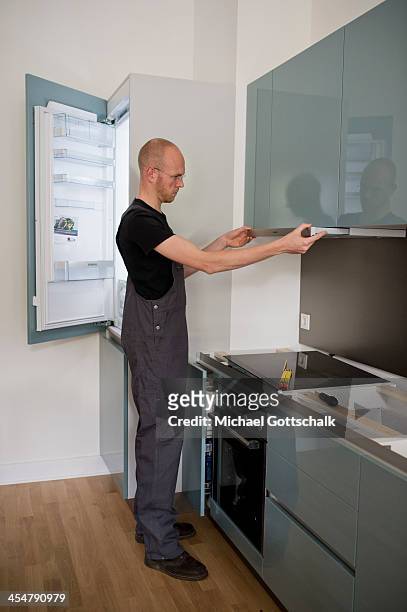 Staged photo of a workman installing an extractor hood in a kitchen on October 25, 2013 in Berlin, Germany.