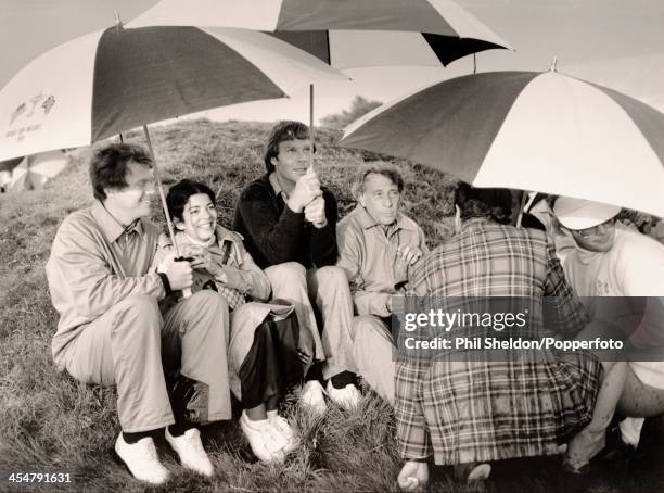 Some of the United States team, from left to right, Tom Watson with his wife Linda, Ben Crenshaw and David Marr sheltering from the rain during the...