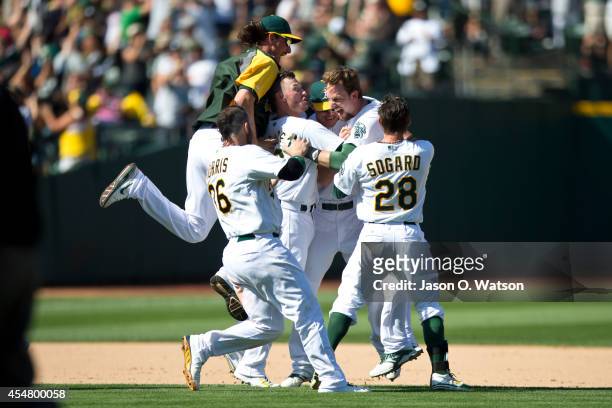 Jed Lowrie of the Oakland Athletics is congratulated by teammates after hitting a walk off single against the Houston Astros during the ninth inning...