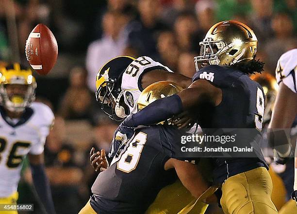 Devin Gardner of the Michigan Wolverines fumbles the ball as he is hit by Joe Schmidt abd Jaylon Smith of the Notre Dame Fighting Irish at Notre Dame...
