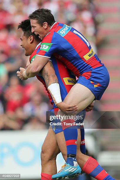 Kurt Gidley of the Knights jumps onto the back of team mate Joey leilua after scoring a try during the round 26 NRL match between the Newcastle...