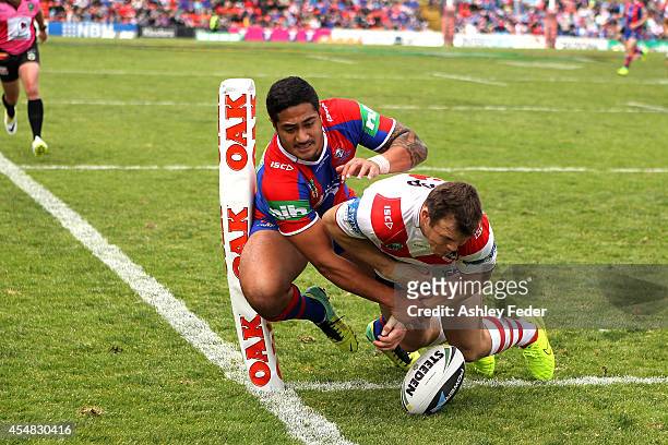 Chanel Mata'Utia of the Knights attempts to score a try with Gerard Beale of the Dragons in defence during the round 26 NRL match between the...