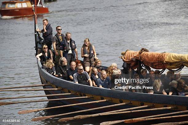 An original replica of a Viking boat, "Sea Stallion from Glendalough" rowed by people accompanied by river police near Oberbaum Bridge going to...
