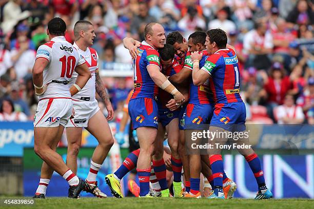 Knights players celebrate a try with Dragons looking dejected during the round 26 NRL match between the Newcastle Knights and the St George Illawarra...