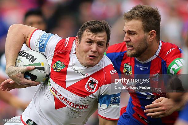 Brett Morris of the Dragons is tackled by Robbie Rochow of the Knights during the round 26 NRL match between the Newcastle Knights and the St George...