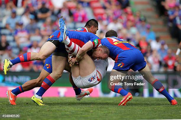 Trent Merrin of the Dragons is tackled by the Knights defence during the round 26 NRL match between the Newcastle Knights and the St George Illawarra...