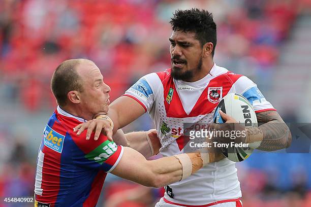 Peter Mata'Utia of the Dragons is tackled by Beau Scott of the Knights during the round 26 NRL match between the Newcastle Knights and the St George...