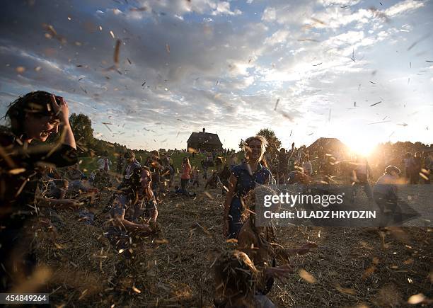 People dance and throw straw during a traditionnal festival in village Ozerco, some 10 km from Minsk, on September 6, 2014. AFP PHOTO / ULADZ HRYDZIN