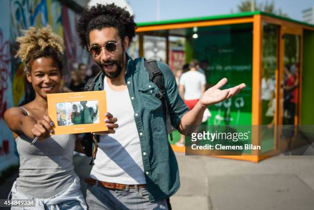 Visitors pose with a picture taken of them at the Nokia Lumia 735 Skype and Selfie Pod at the East Side Gallery on September 6, 2014 in Berlin,...