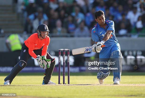 Dohni of India hits out as Jos Buttler of England looks on during the NatWest International T20 2014 match between England and India at Edgbaston on...