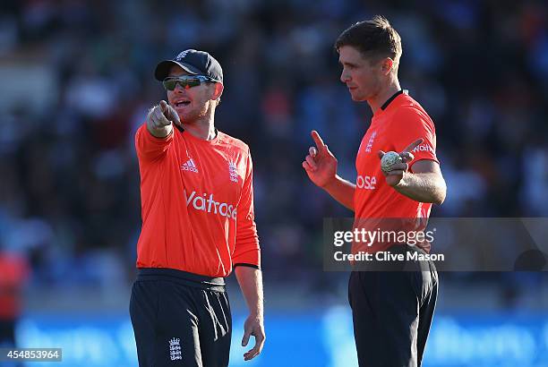 Eoin Morgan of England takls with Chris Woakes of England as he prepares to bowl the last ball during the NatWest International T20 2014 match...