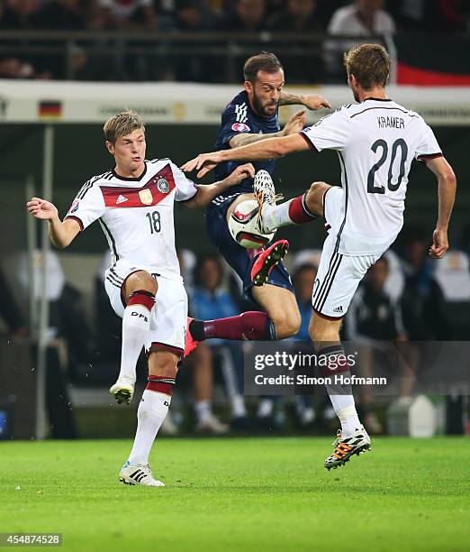 Steven Fletcher of Scotland is challenged by Toni Kroos and Christoph Kramer of Germany during the EURO 2016 Qualifier match between Germany and...