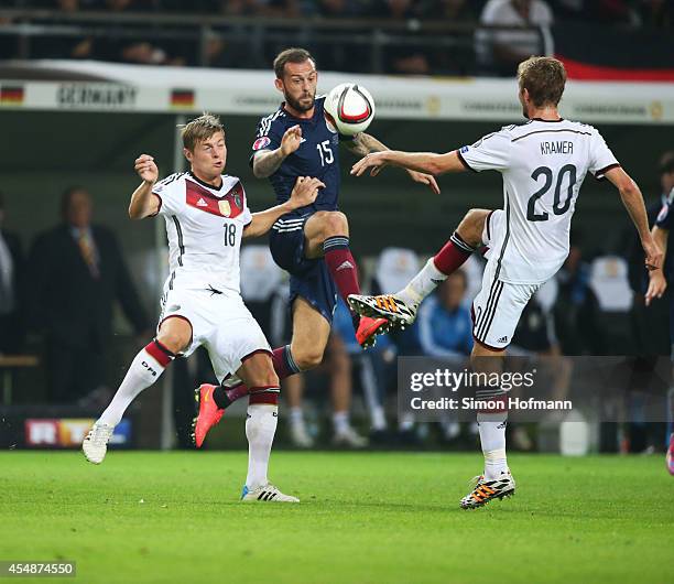 Steven Fletcher of Scotland is challenged by Toni Kroos and Christoph Kramer of Germany during the EURO 2016 Qualifier match between Germany and...