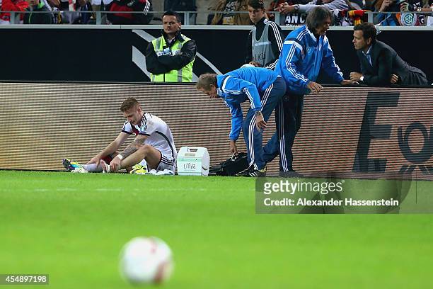 An injured Marco Reus of Germany is given treatment whilst team doctor Hans-Wilhelm Mueller-Wohlfahrt talks to team manager Oliver Bierhoff during...