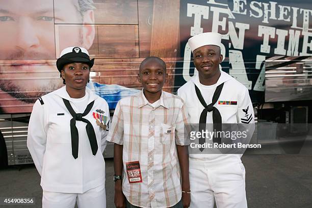 Military USO family, Roland Kiendrebeogo , Marie Esther Kiendrebeogo and their son Oswald Kiendrebeogo stand backstage prior to a Blake Shelton...