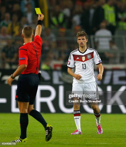 Referee Svein Oddvar Moen shows a yellow card to Thomas Mueller of Germany during the EURO 2016 Qualifier match between Germany and Scotland at...