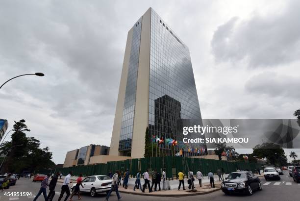 People walk past the provisional headquarters of the African Development Bank on September 8, 2014 in Abidjan after a ceremony marking the effective...