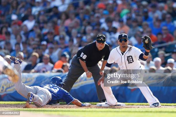 Norichika Aoki of the Kansas City Royals dives back to first base ahead of the throw to Victor Martinez of the Detroit Tigers in the third inning of...