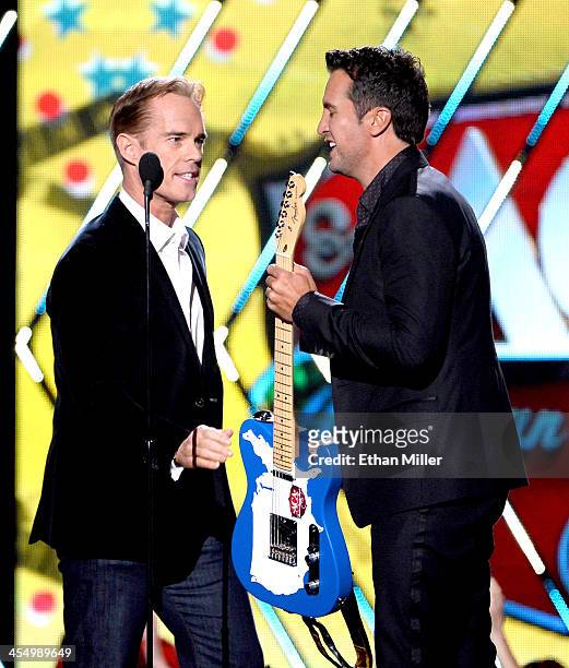 Recording artist Luke Bryan accepts the award for Artist of the Year from presenter Joe Buck onstage during the American Country Awards 2013 at the...