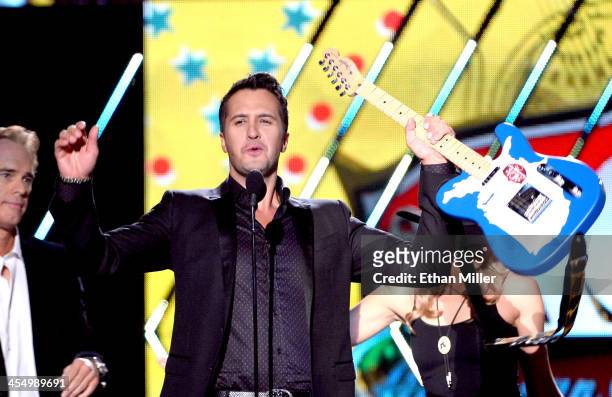 Recording artist Luke Bryan accepts the award for Artist of the Year from presenter Joe Buck onstage during the American Country Awards 2013 at the...