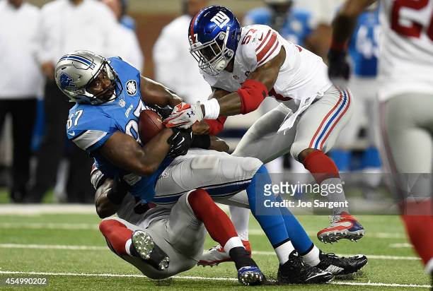 Brandon Pettigrew of the Detroit Lions is brought down in the first quarter by Jon Beason and Jacquian Williams of the New York Giants during a game...