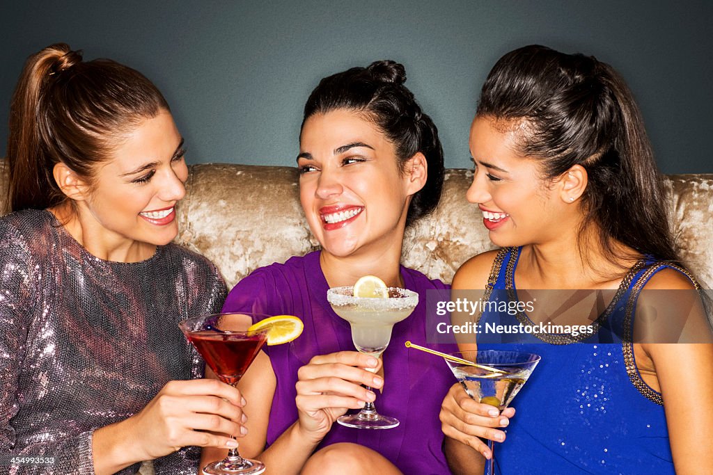 Friends With Cocktail Drinks Sitting On Sofa In Nightclub