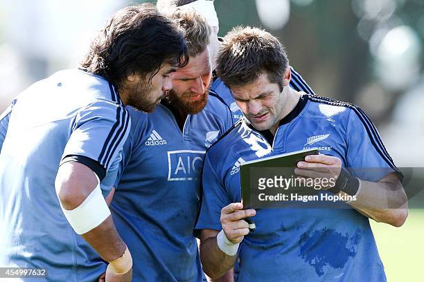 To R, Steven Luatua, Kieran Read and Richie McCaw look at an iPad during a New Zealand All Blacks training session at Hutt Recreation Ground on...