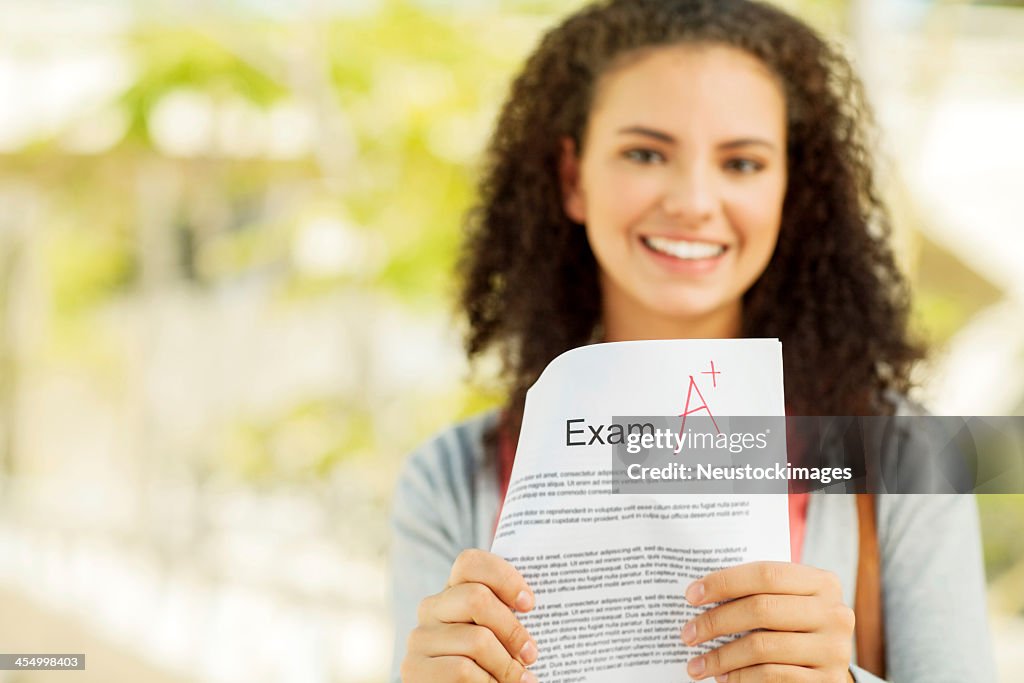 Student Showing Exam Result With A+ Grade On Campus