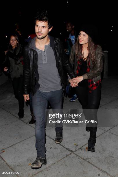 Taylor Lautner and Marie Avgeropoulos are seen arriving at Staples Center on December 09, 2013 in Los Angeles, California.