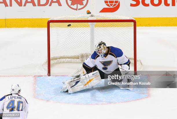 Maxim Lapierre of the St. Louis Blues watches as the puck goes over the shoulder of teammate Brian Elliott on a shot by Bryan Little of the Winnipeg...