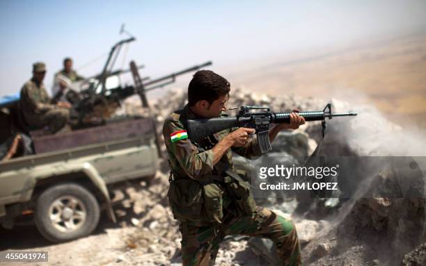 An Iraqi Kurdish Peshmerga fighter fires at Islamic-State militant positions, from his position on the top of Mount Zardak, a strategic point taken 3...