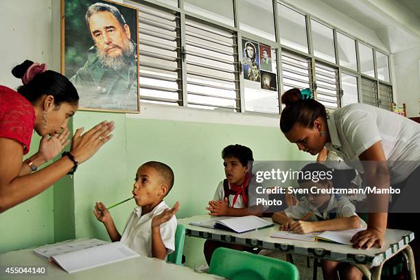 Cuban mentally and physically disabled children take part in a lesson under the image of Cubas revolution leader Fidel Castro, in the special needs...