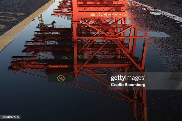 Gantry cranes are reflected in a puddle at the Hanjin Shipping Co. Busan New Port terminal in Busan, South Korea, on Tuesday, Dec. 10, 2013. South...