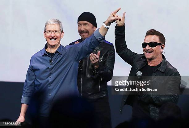Apple CEO Tim Cook greets the crowd with U2 singer Bono as The Edge looks on during an Apple special event at the Flint Center for the Performing...