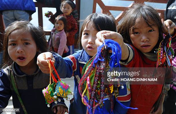 This picture taken on December 8, 2013 shows Hmong ethnic children trying to sell souvenir items to tourists at a village in the popular tourist...