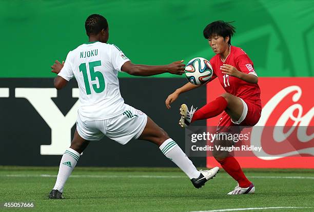 Choe Un Hwa of Korea DPR and Ugo Njoku of Nigeria in action during the FIFA U-20 Women's World Cup Canada 2014 Semi Final match between Korea DPR and...