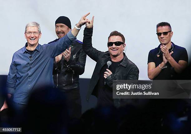 Apple CEO Tim Cook greets the crowd with U2 singer Bono as The Edge and Larry Mullen Jr look on during an Apple special event at the Flint Center for...