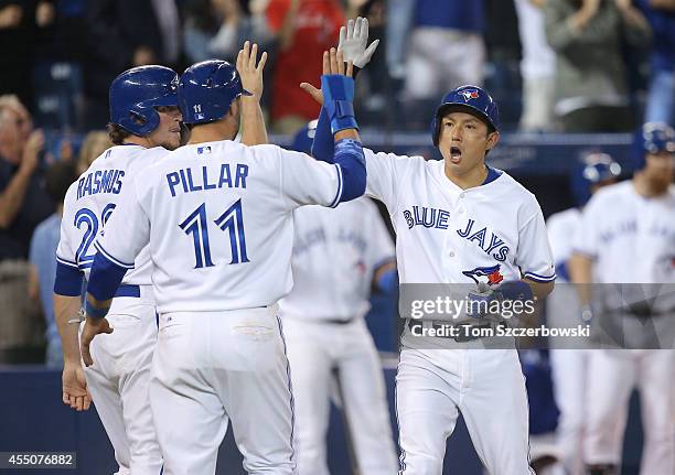 Munenori Kawasaki of the Toronto Blue Jays celebrates with Kevin Pillar and Colby Rasmus after they all scored on a bases-clearing double in the...