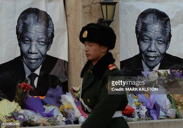 Chinese para-military policeman patrols past portraits at a memorial to the late South African leader Nelson Mandela outside the South African...