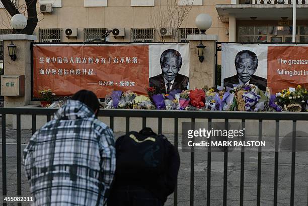 Chinese students bow before portraits at a memorial to the late South African leader Nelson Mandela outside the South African embassy in Beijing on...